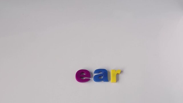 Learning and education concept, hand arranging colorful plastic letters to spell the word learn in a stop motion animation sequence on a white background.