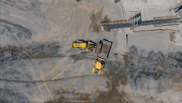Aerial view of heavy machinery at work in a quarry, dust swirling around the site, Cape Town, Western Cape, South Africa.