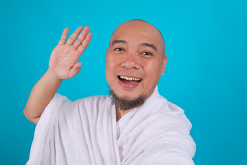 Naklejka premium Cheerful Muslim Pilgrim in White Ihram Waving Hand for Selfie