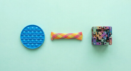 Set of sensory fidget toys including pop it, marble mesh and infinity cube on green background