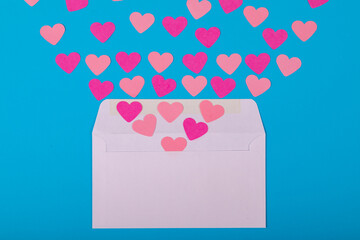 Directly above view of pink hearts coming out from white envelope blue background, copy space