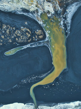 Aerial view of swirling ochre discharge contrasts starkly against the deep blue waters, creating a mesmerizing display of nature's artistry, Selfoss, Sveitarfelagid Arborg, Iceland.