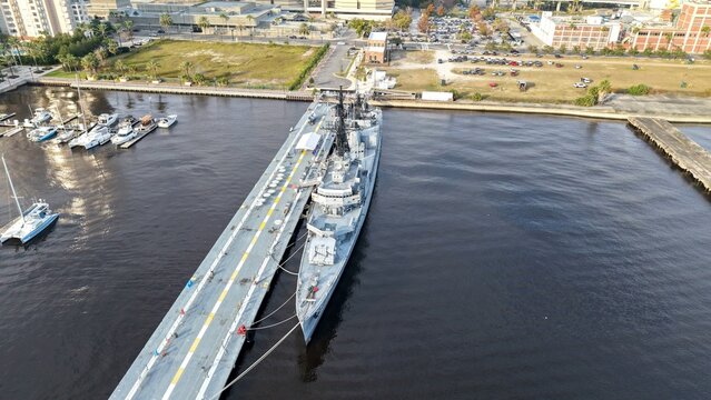 Aerial view of the USS Orleck Naval Museum, a striking silhouette against the dark water, docked next to a concrete pier, Jacksonville, Florida, United States.