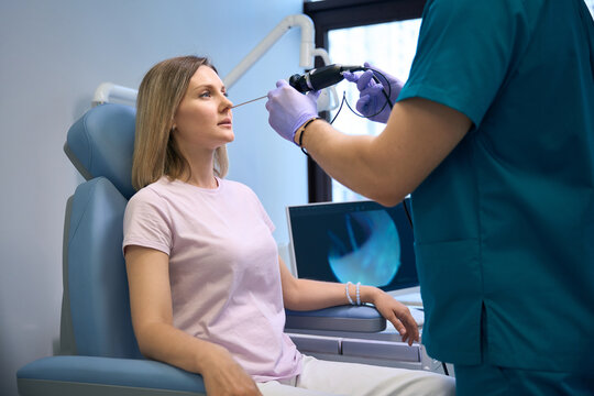 Male ENT doctor examining female patient nose using video ENT endoscope