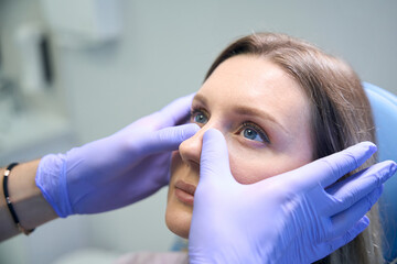 ENT doctor examines and palpates the nasal septum of female patient