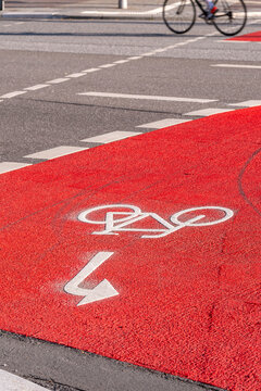 Bicycle bike lane arrow marking on red asphalt road in Hamburg indicating direction route guidance and steady urban traffic flow