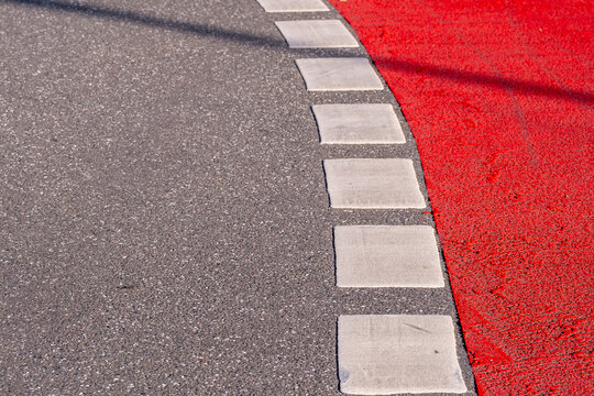 Red asphalt bike lane curve along curb in Hamburg with urban road marking texture showing guidance for bicycle traffic routes