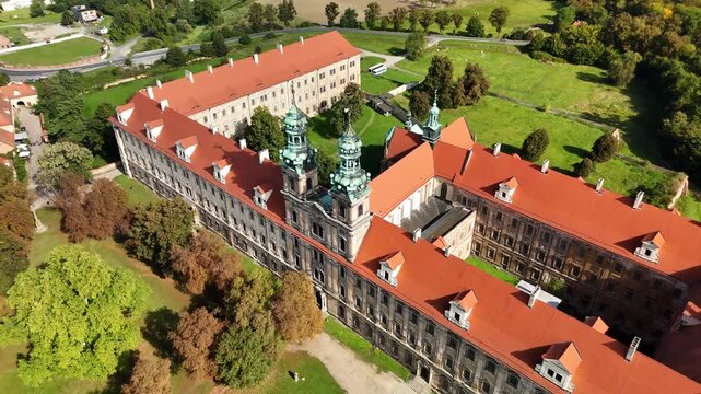 Aerial drone view of Cistercian Abbey in Lubiąż, Lower Silesia, Poland, surrounded by lush green forests, river, and scenic countryside landscape, historic monastery and cultural heritage site