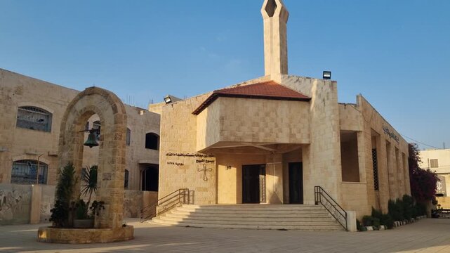 Evening sunlight illuminates the Modern Christian Church, also known as the Church of the Nazarene, on Palestine Street in Madaba, Jordan, highlighting its modern architecture and warm light