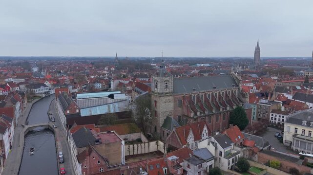 Aerial orbit shot of the baroque St. Walburga&rsquo;s Church in Bruges, Belgium. Revealing colorful riverside houses and historic canals in the medieval city center.