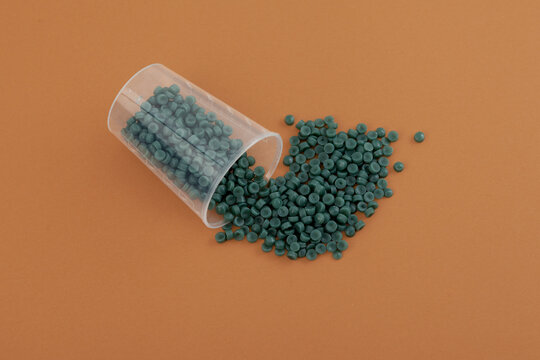 Reprocessed Polypropylene (post-industrial). Secondary plastic polymer. Recycled Polypropylene or rPP granules spilled out of plastic cup