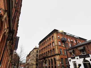 Fototapeta premium Historic red brick buildings in Manchester city center with arched windows and street lamp