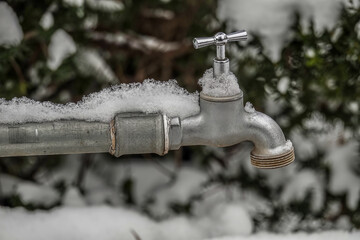 Wasserhahn draussen bedeckt mit Schnee