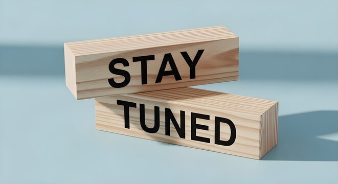 Wooden blocks featuring the phrase stay tuned are stacked precariously signaling an upcoming announcement or future event.