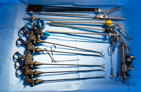 Top view of various laparoscopic and neurosurgical instruments. Overhead shot of surgical tools, graspers, and trocars arranged on a blue surface.