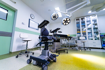 Fototapeta premium High tech surgical room with medical equipment and cabinets. Interior of modern operating theater with overhead LED lamps, surgical table, and storage furniture.