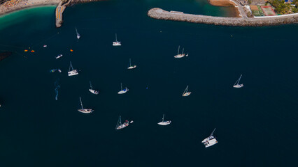 Aerial view of several sailing yachts and catamarans anchored in a calm bay © Андрей Нелупов