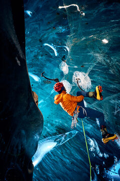 Man climbing frozen ice cave in winter mountains