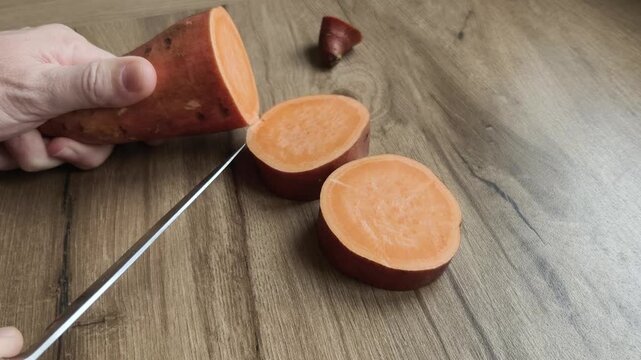 Sweet potato being cut by hand on kitchen table