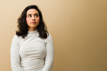 Fototapeta premium Woman looking away, generating ideas and making decisions. Her contemplative expression conveys deep thought on a neutral background