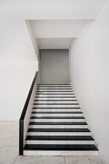 Minimal white interior staircase with marble steps and handrail