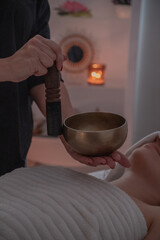 Practitioner striking singing bowl in spa environment