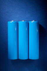 Three blue rechargeable lithium batteries, size 18650, on a blue table.