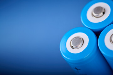 Three blue rechargeable lithium batteries, size 18650, on a blue table.