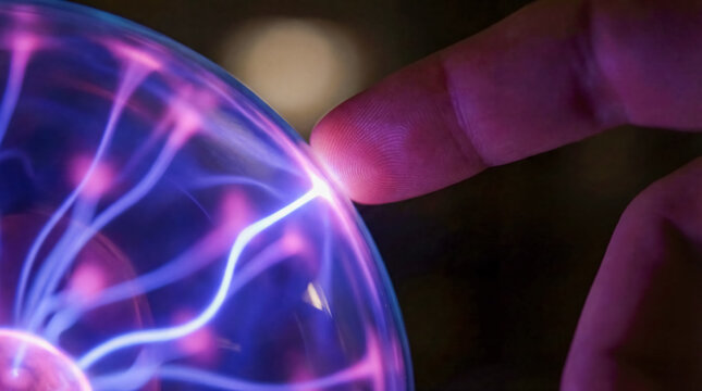 Hand touching plasma ball lamp with electric lightning science physics experiment education background copy space magic energy flow technology