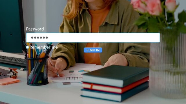 User types password into the login form on a website while sitting at a desk with flowers and a planner nearby.
