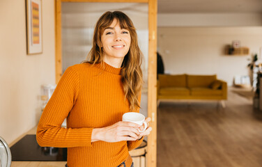 Smiling woman holding a coffee cup in cozy home