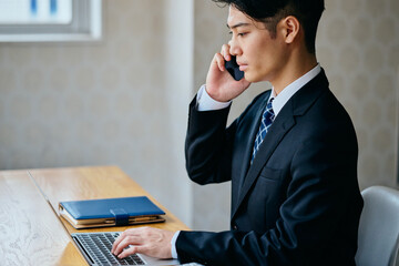 Businessman Talking on Smartphone While Working on Laptop in Office