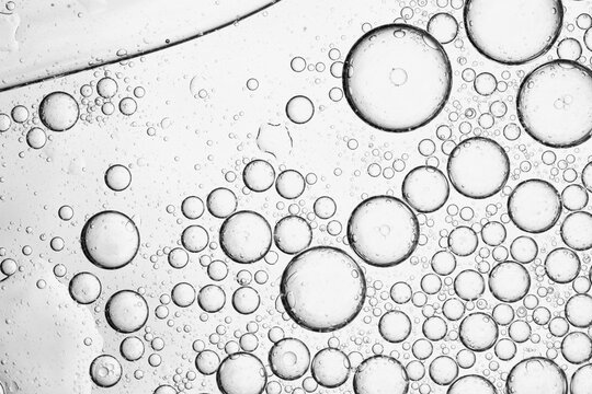 Abstract Macro of Oil Bubbles in Water on Grey Background,A high-quality, monochrome macro photograph showcasing the intricate patterns of oil droplets and bubbles suspended in water. The composition 