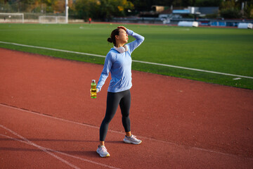 Obraz premium Young asian woman resting after outdoor workout on running track