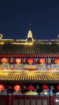 Vertical video: Recording camera holding view on temple facade at night, for showing lit spire