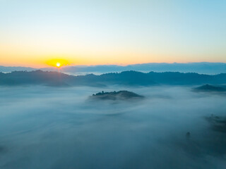 Aerial view of flowing fog waves on mountain tropical rainforest,Bird eye view image over the clouds Amazing nature background with clouds and mountain peaks in Thailand