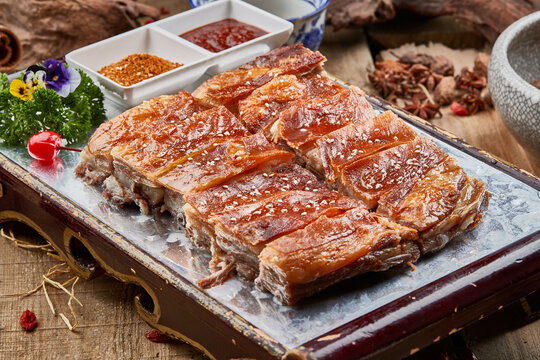 Mongolian roasted lamb chops, served in a red lacquered tray, are placed on a camphor wood cutting board.