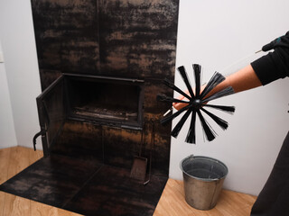 Man preparing to clean a modern indoor fireplace with a professional chimney brush.
