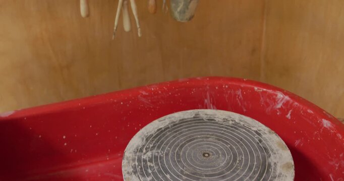 Pottery gear, hanging tools, handmade pots, and plates on a workshop shelf