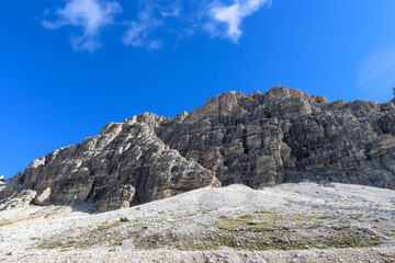 Fototapeta premium Dolomites cliffs captured from below, rising into blue sky with scattered clouds