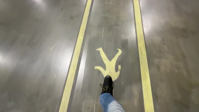 Wide angle point of view walking between yellow safety lines on a polished warehouse floor