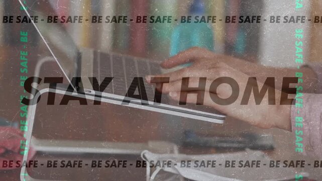 Animation of words Be Safe Stay At Home flashing and making a frame over a person using a laptop