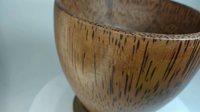 Wooden bowl, traditional, unique handicraft art with high aesthetic value, rotating on a stand with a white background.