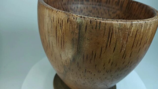 Wooden bowl, traditional, unique handicraft art with high aesthetic value, rotating on a stand with a white background.
