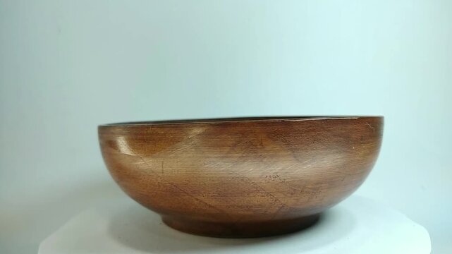 Wooden bowl, traditional, unique handicraft art with high aesthetic value, rotating on a stand with a white background.
