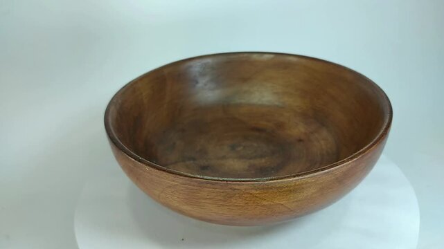 Wooden bowl, traditional, unique handicraft art with high aesthetic value, rotating on a stand with a white background.