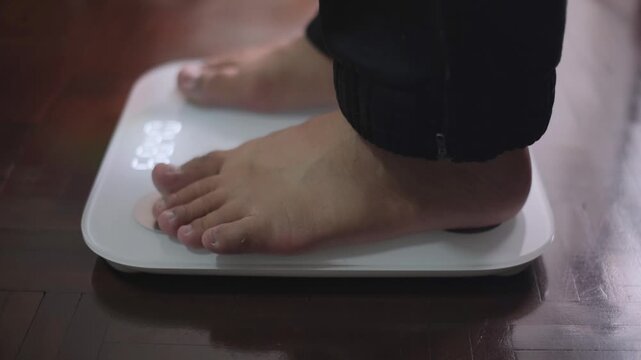 Feet stepping onto a weighing scale and stepping off creating a heavy thumping and creaking sound