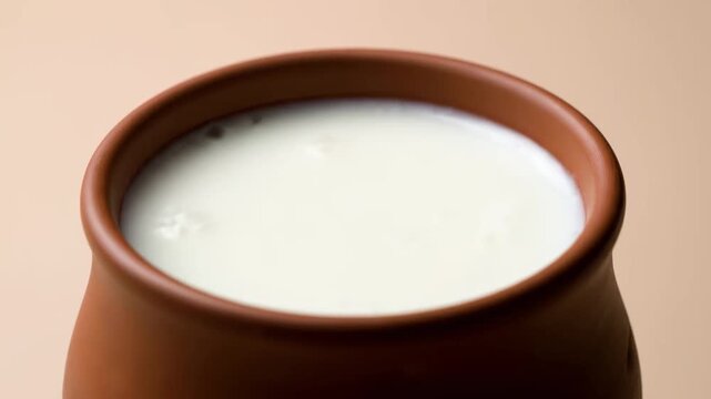 Close-up of Fresh Homemade Yogurt (Dahi or Curd) served in a traditional Indian terracotta clay pot (Kulhad) on a soft beige background.