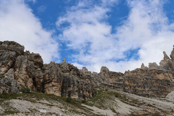 Dolomites cliffs rising dramatically under a blue sky dotted with white clouds
