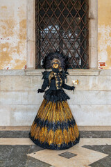 Full-length view of an elegant Venetian carnival costume in black and gold during Carnival celebrations in Venice, Italy